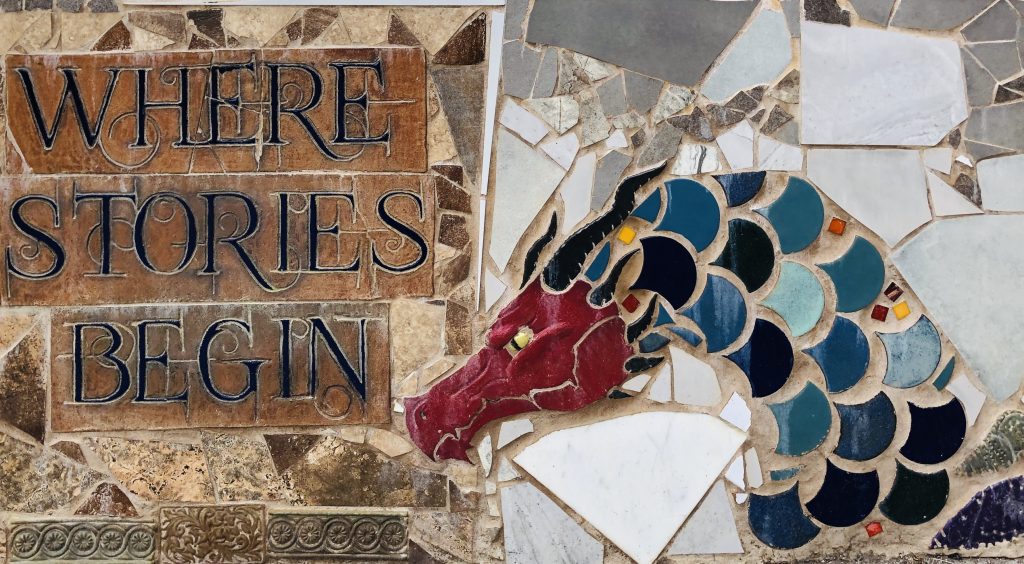 section of library brick wall mural with dragon and the tagline, "Where Stories Begin."